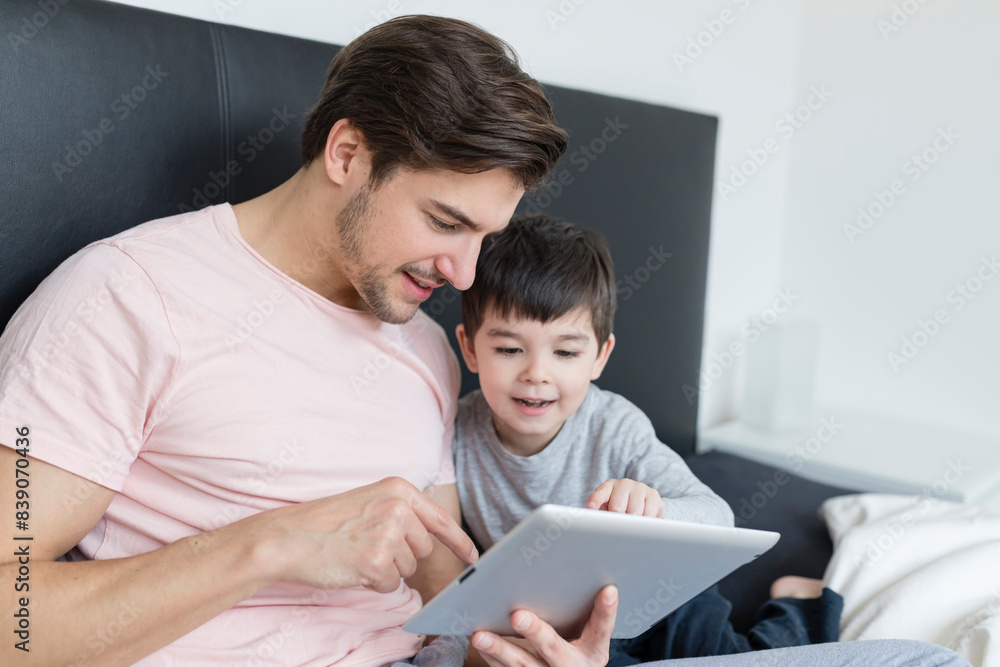 Father and son looking at tablet in bed Father and son looking at tablet in bed