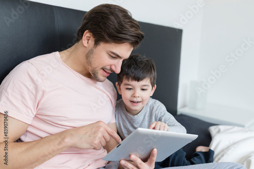 Father and son looking at tablet in bed