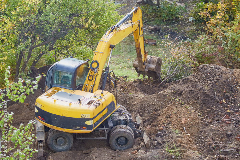 Yellow excavator begins to dig a pit Yellow excavator begins to dig a pit