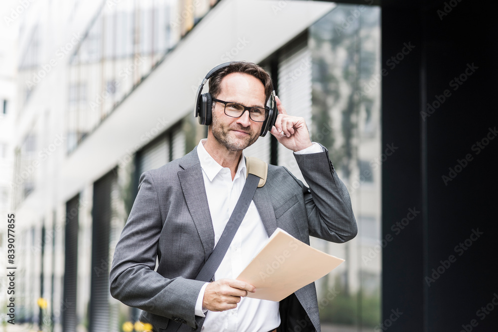 Portrait of smiling businessman with documents and headphones Portrait of smiling businessman with documents and headphones