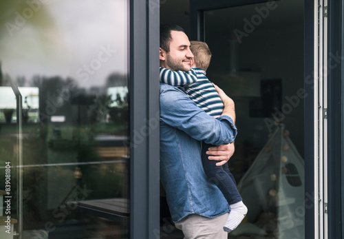 Obraz na płótnie Father hugging son at terrace door at home w salonie