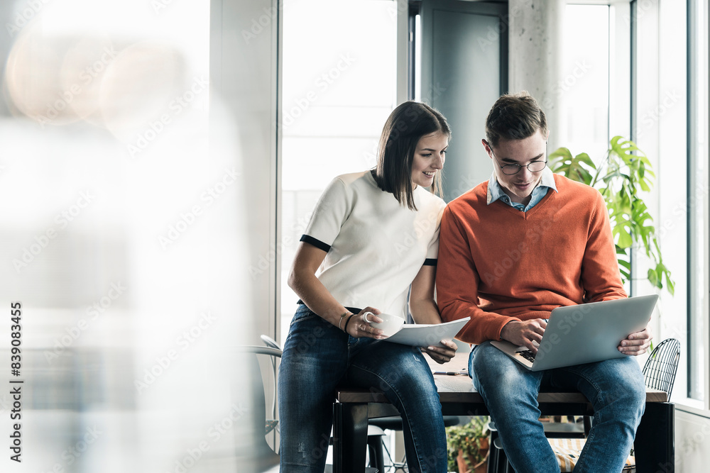 Casual businessman and woman with laptop meeting in office