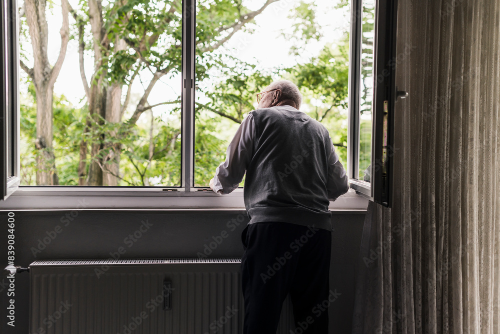 Back view of senior man looking out of window
