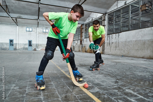 Boy practicing roller hockey with father on court photo