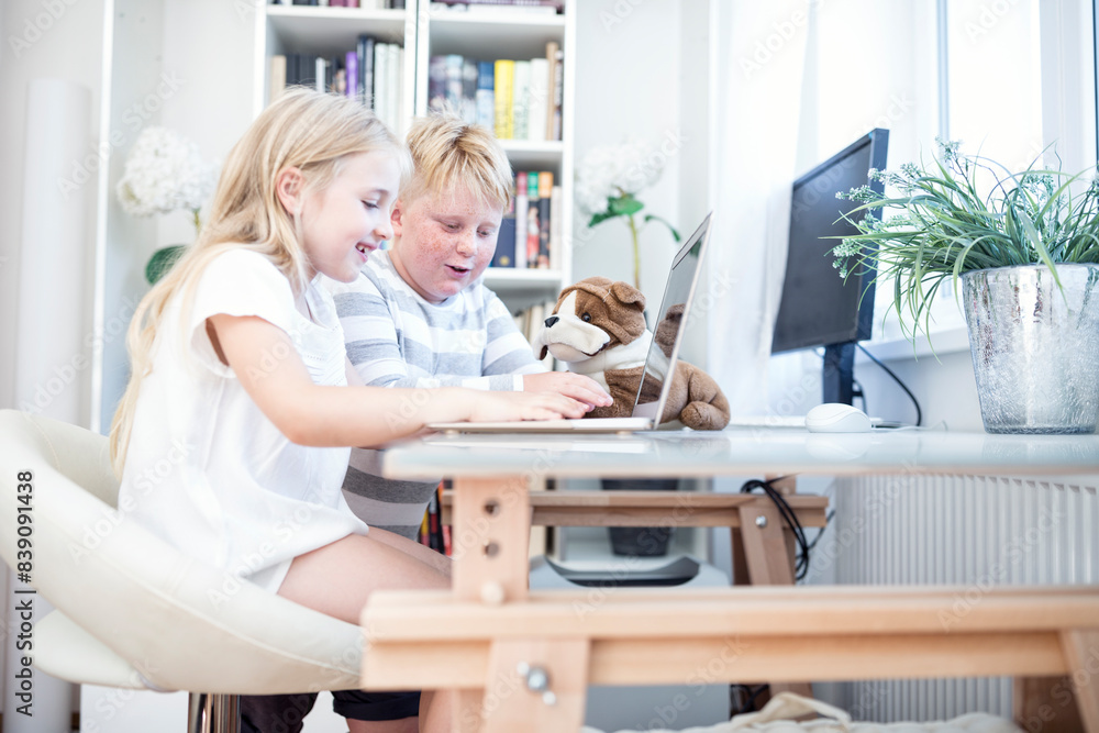 Brother and sister with cuddly toy using laptop together Brother and sister with cuddly toy using laptop together