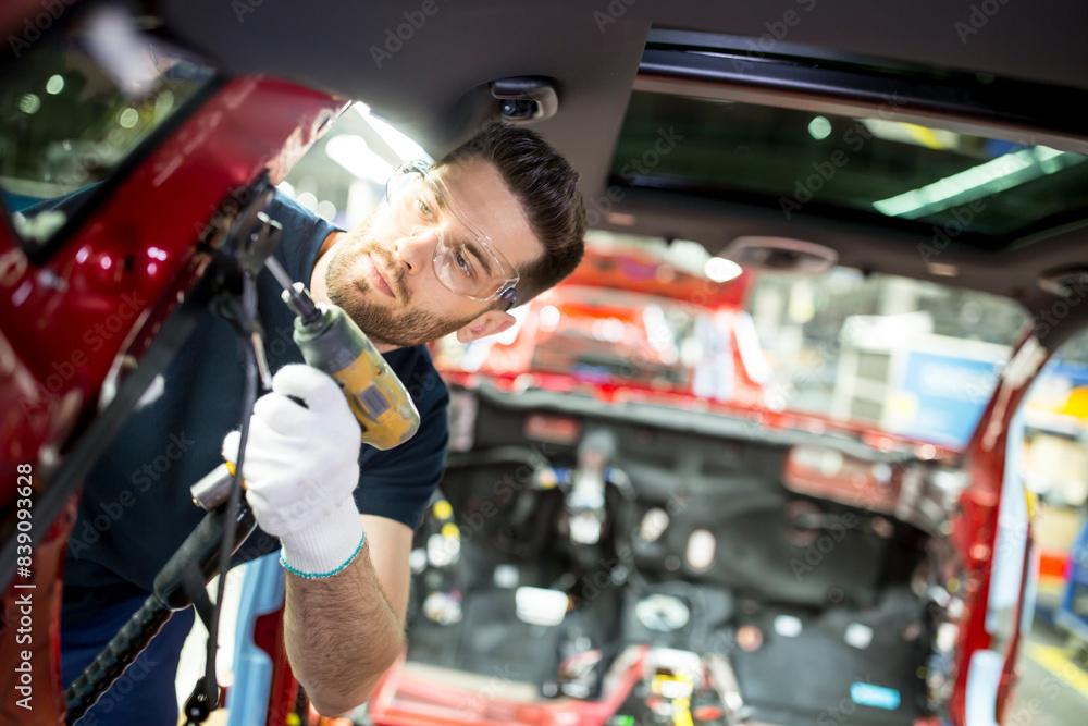 Man working at bodywork in modern car factory Man working at bodywork in modern car factory