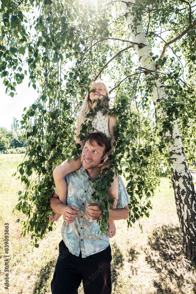 Father carrying daughter piggyback under a birch tree Father carrying daughter piggyback under a birch tree