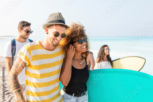 Group of friends walking on the beach, carrying surfboards photo