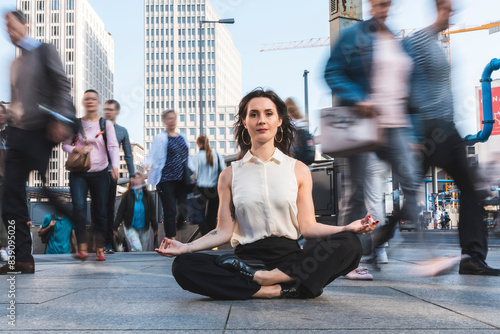 Young businesswoman practising yoga in the city at rush hour, Berlin, Germany