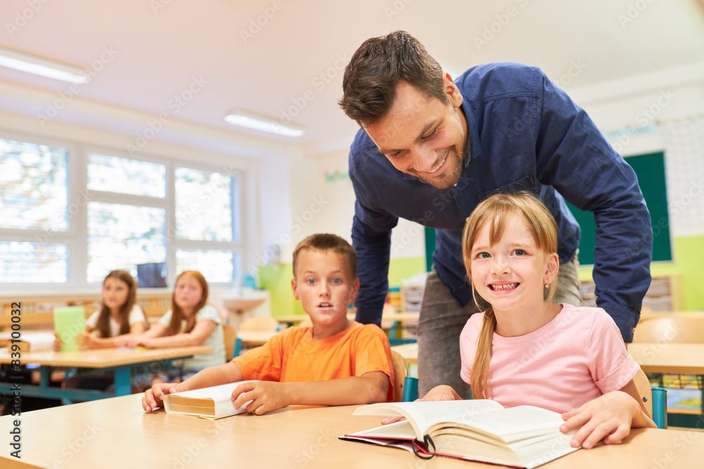 Teacher standing near students reading books Teacher standing near students reading books