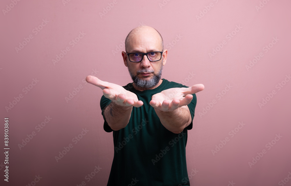 Naklejka premium Bearded bald man with prescription glasses showing his palm.