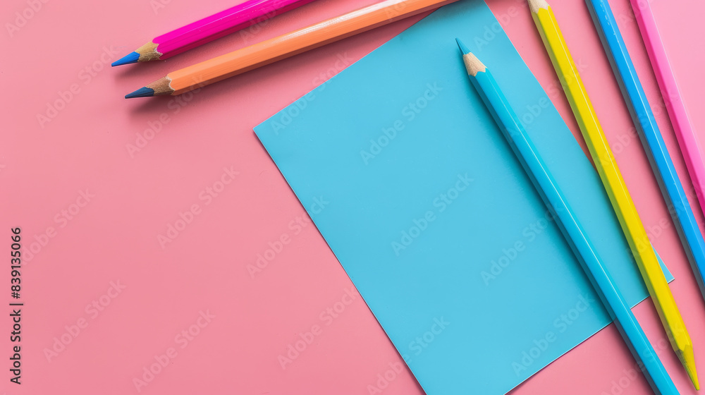 A creative arrangement of colored pencils and paper on pink background. A creative arrangement of colored pencils and paper on pink background.