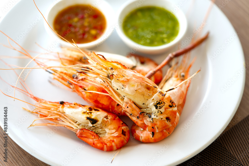 Grilled prawns with two different sauce to dipping, green sauce seafood and sweet red chili sauce. Grilled prawns in dish with natural light from window, close up food image. Grilled prawns with two different sauce to dipping, green sauce seafood and sweet red chili sauce. Grilled prawns in dish with natural light from window, close up food image.