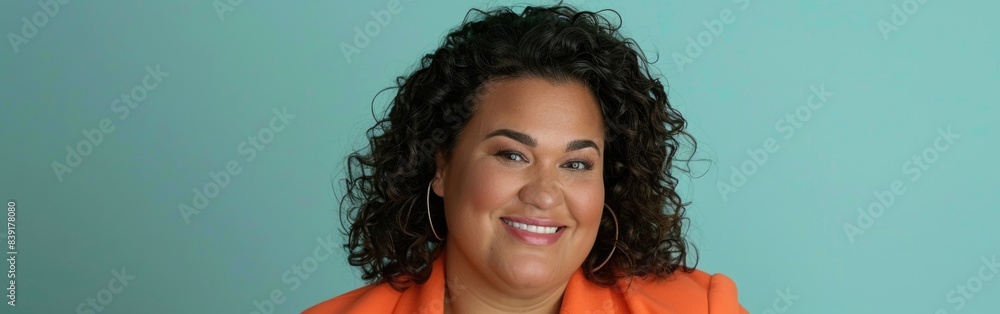 A plus size businesswoman smiles at the camera while wearing a bright orange blazer A plus size businesswoman smiles at the camera while wearing a bright orange blazer