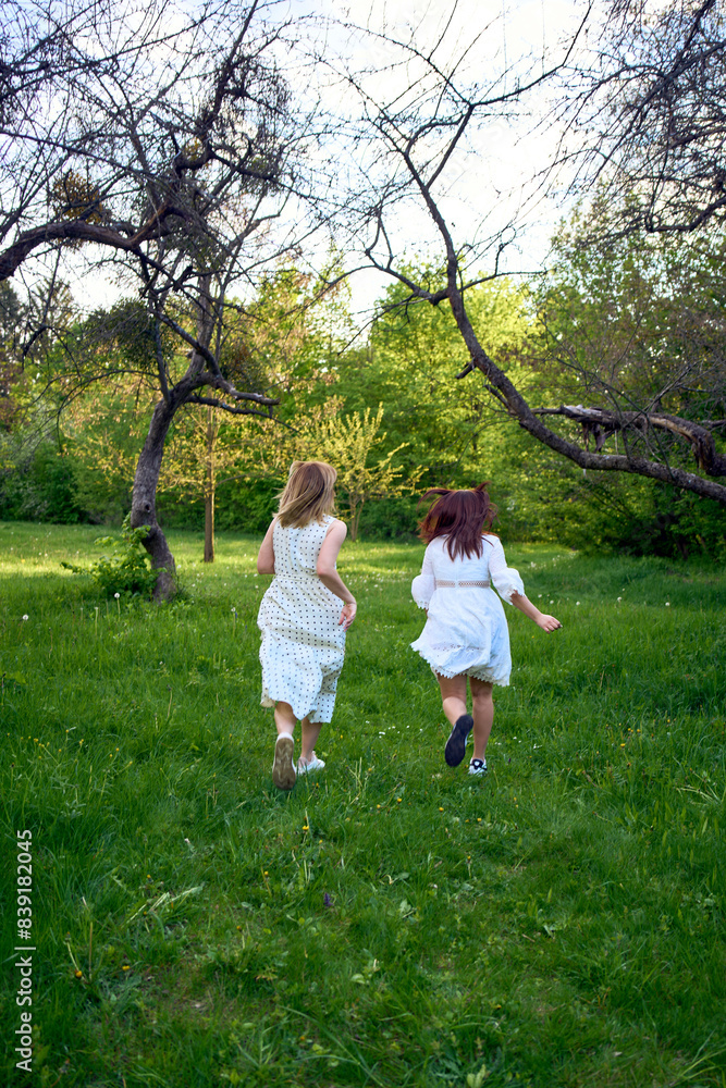 Fototapeta premium a mother and her teenage daughter are hugging and playing in the garden