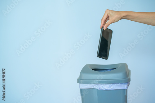 Female putting smartphone in a trash bin, concept of digital detox