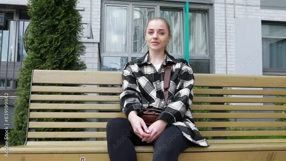 Young Woman Relaxing on a Park Bench in an Urban Setting During Springtime Young Woman Relaxing on a Park Bench in an Urban Setting During Springtime