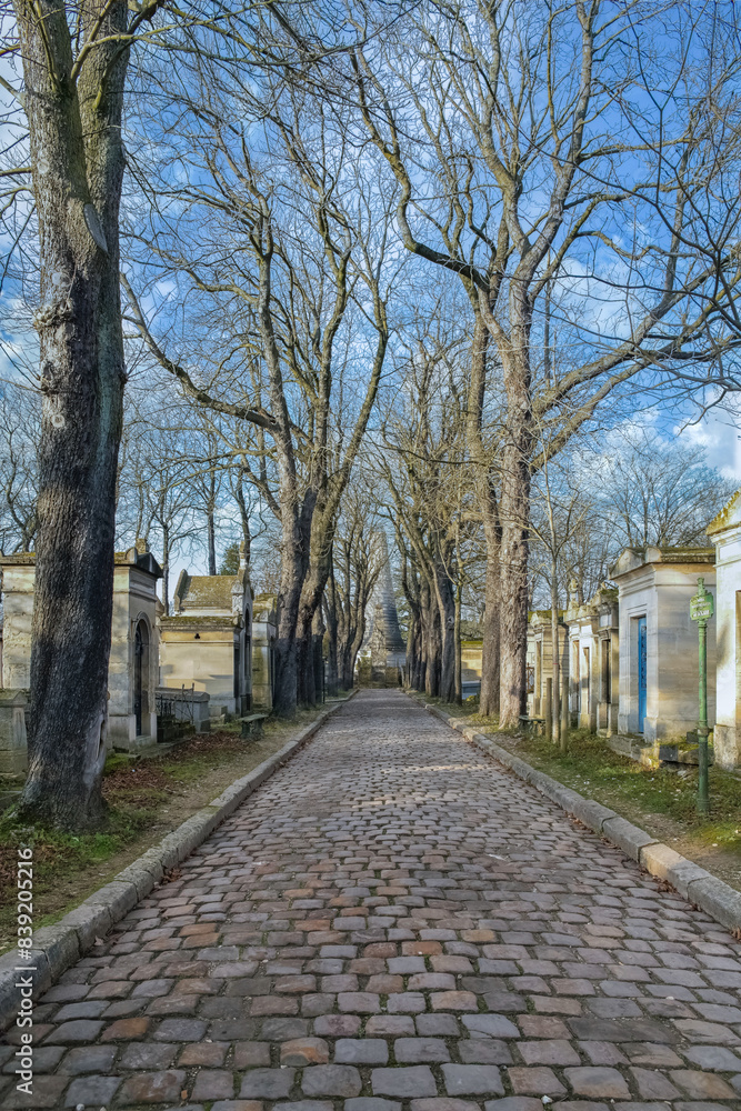 Scenic view of the Pere-Lachaise cemetery, cobbled alley with graves in winter in Paris, France Scenic view of the Pere-Lachaise cemetery, cobbled alley with graves in winter in Paris, France
