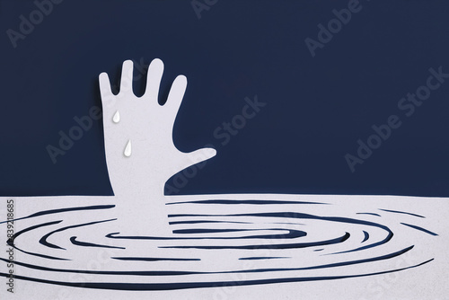 A paper cut image of a hand about to drown. Needing help in times of crisis. Save from danger situation. Struggling for survival.