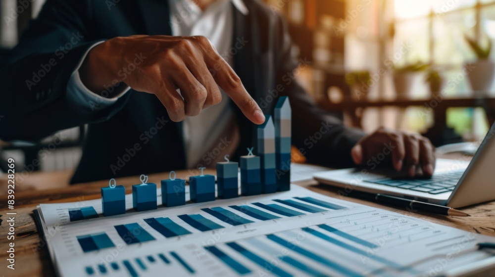 A businessman pointing to a rising bar graph, indicating positive growth and success in business performance A businessman pointing to a rising bar graph, indicating positive growth and success in business performance