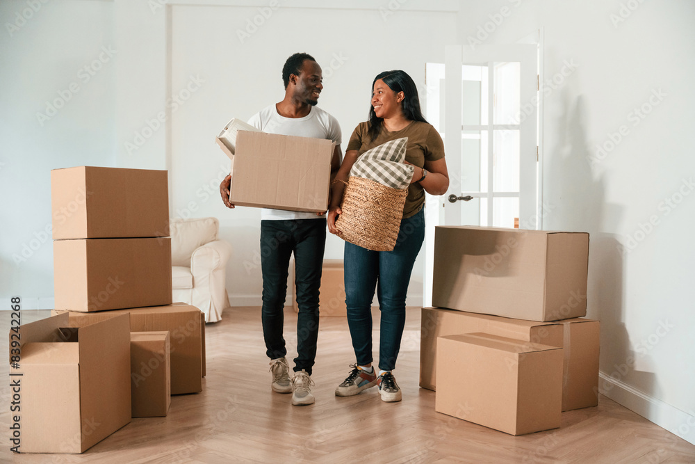Walking in, holding boxes. African American couple are moving into new house Walking in, holding boxes. African American couple are moving into new house