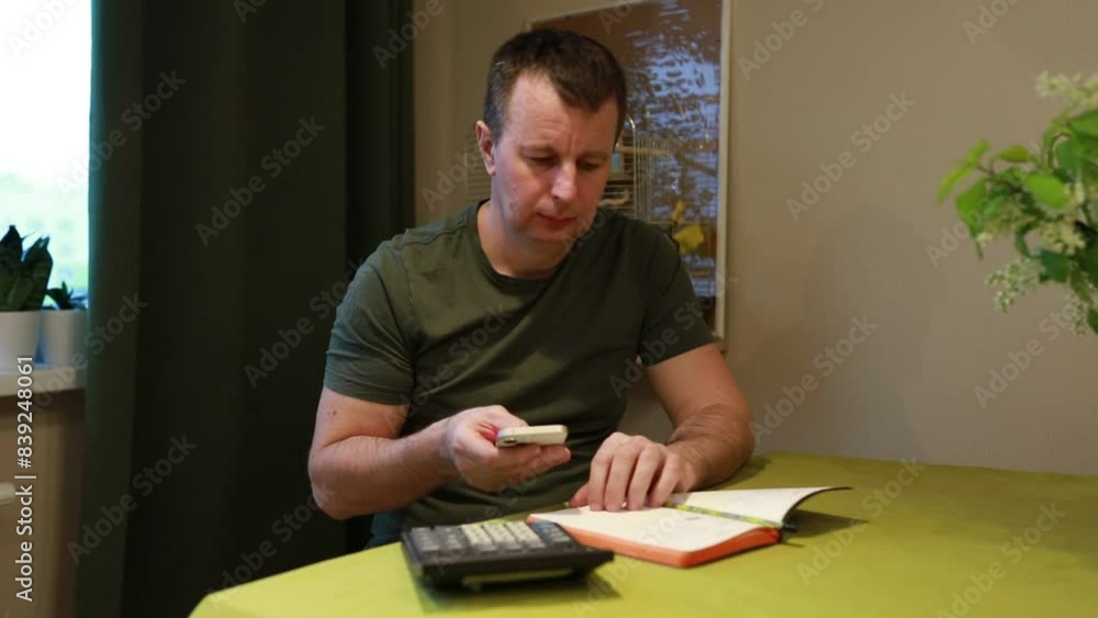 Man Sitting at Table With Book and Calculator Man Sitting at Table With Book and Calculator