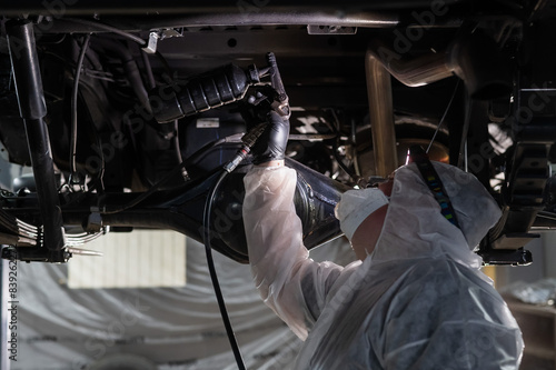 The master sprays an anti-corrosion compound on the bottom of the car. 