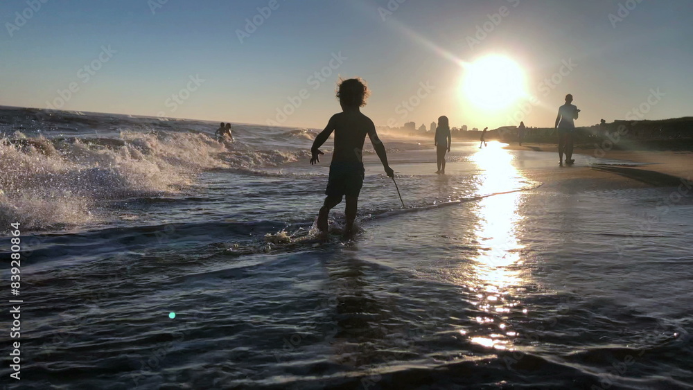 Fototapeta premium Little boy at the beach playing, silhouette