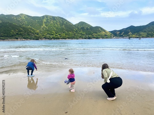 A family enjoying the beautiful sand and ocean scenery of Atashika Beach, with jungle in the background, on a beautiful day in Kumano, in the Mie Prefecture, Japan photo