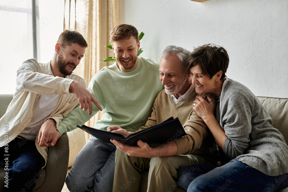 A gay couple sits with parents, looking at a photo album together. A gay couple sits with parents, looking at a photo album together.