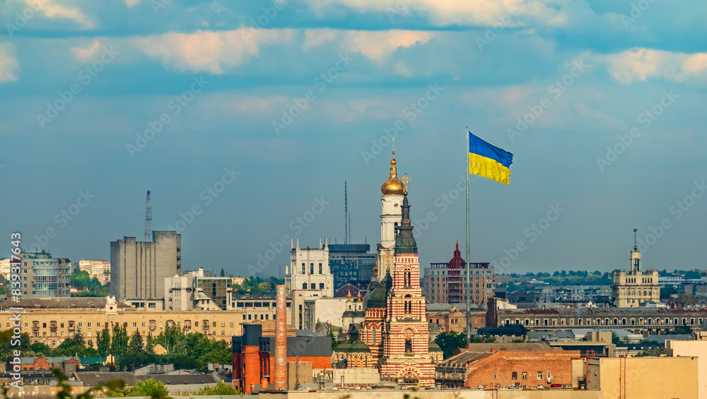 Fototapeta premium Cityscape of Kharkiv city with buildings, church and Ukrainian flag. Panoramic view of the city center