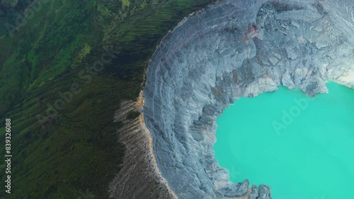 Top aerial view of turquoise sulfur water lake, surrounded by rock cliff at Kawah Ijen volcano in East Java, Indonesia.