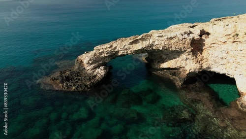 Love bridge near Ayia Napa in Cyprus. Aerial panoramic view of summer rocky landscape in Cavo Greco National park, romantic turquoise sea waves and natural arch of bridge from rocks in water