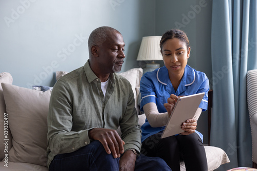 Private healthcare nurse using a digital tablet for a patient health check in their home