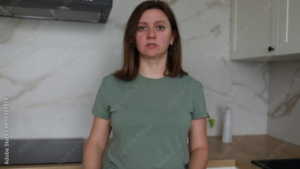 Young Woman in Green T-Shirt Standing in Modern Kitchen Expressing Surprise Young Woman in Green T-Shirt Standing in Modern Kitchen Expressing Surprise
