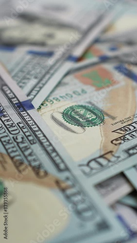 Hundred dollar bills falling on spinning table in a pile of cash. A heap of money growing larger and larger as additional banknotes raining down. Concept of business and finance