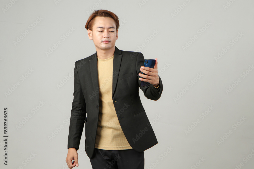 portrait of happy asian businessman wearing suit holding mobile phone isolated background. portrait of happy asian businessman wearing suit holding mobile phone isolated background.