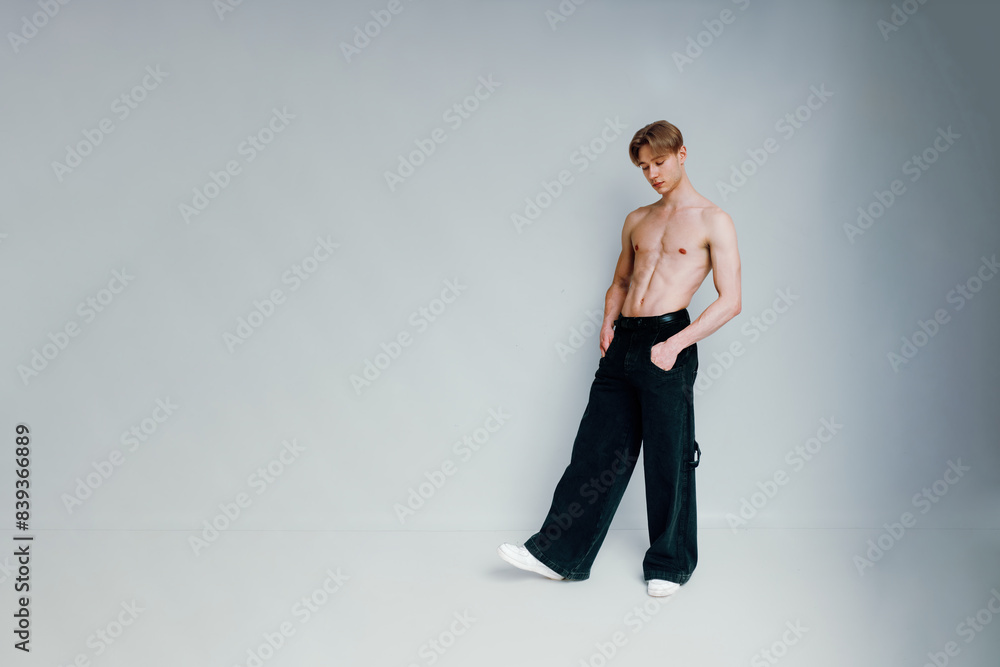 handsome shirtless guy stands in a white background studio, looking down at the floor with his hands in the pockets of his jeans, exuding a youthful and stylish vibe handsome shirtless guy stands in a white background studio, looking down at the floor with his hands in the pockets of his jeans, exuding a youthful and stylish vibe