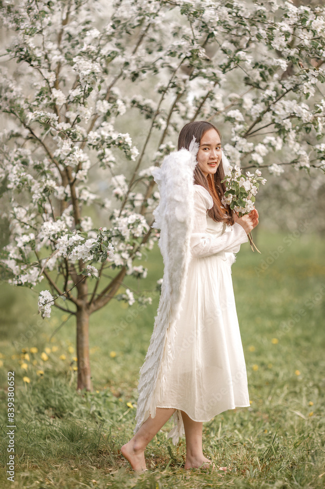 A beautiful woman angel stands in a blooming apple orchard. Spring A beautiful woman angel stands in a blooming apple orchard. Spring