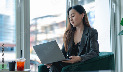 Smiling young asian businesswoman using computer at home office workplace, happy korean employee working on laptop, attractive japanese or chinese woman student studying communicating online with pc