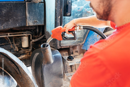 Close-up of Young Farmer Refueling a Tractor With a Gas Pump in the Countryside During Daytime