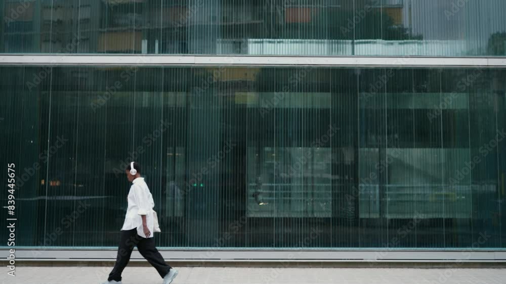 Confident Black woman in white shirt and headphones walks by modern glass building, enjoying music.Female carries tote bag, style and technology-savvy confidence. copy space for text. Urban lifestyle
Confident Black woman in white shirt and headphones walks by modern glass building, enjoying music.Female carries tote bag, style and technology-savvy confidence. copy space for text. Urban lifestyle