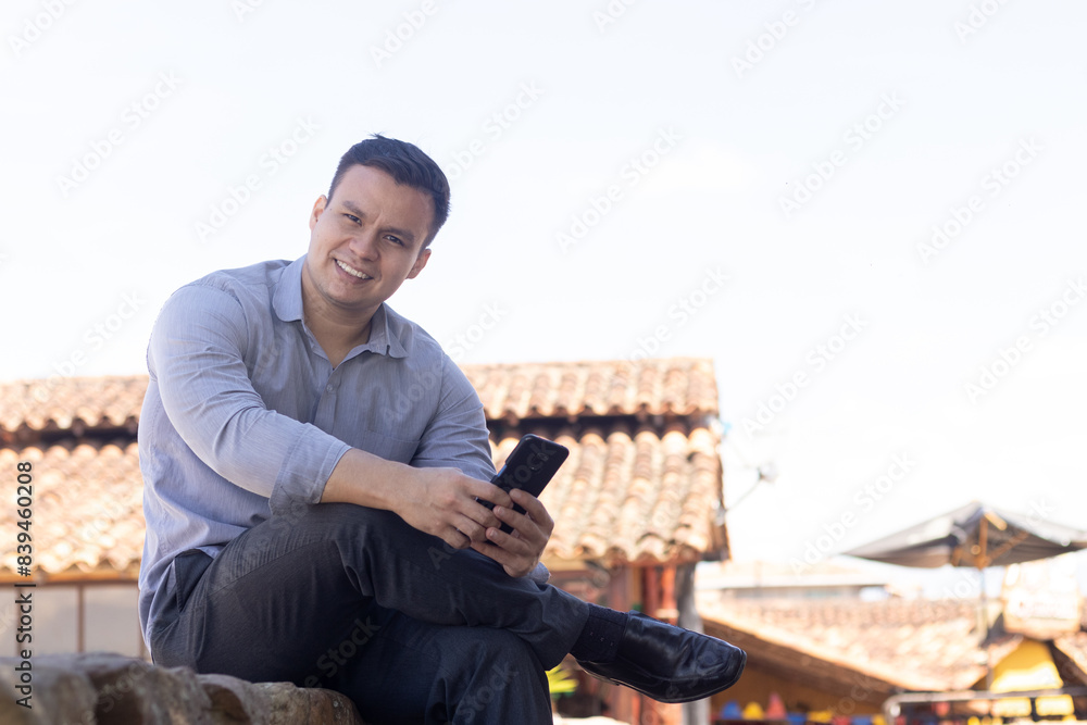 latin man looking at his cell phone sitting latin man looking at his cell phone sitting