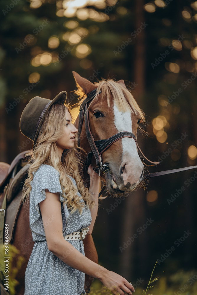Obraz premium A young beautiful woman walks with her horse in the forest in early autumn. Walking with a horse in the forest.