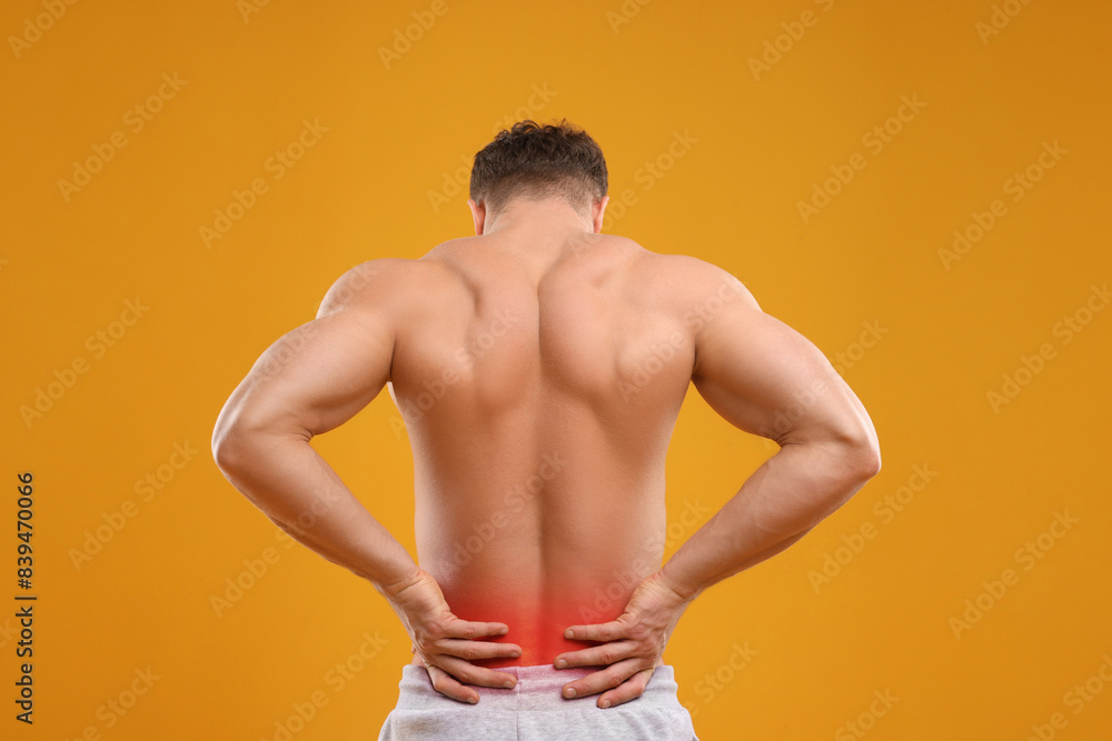 Fototapeta premium Man suffering from pain in lower back on orange background