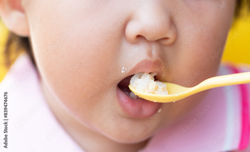 Child eating rice with a spoon close-up,Close up infant baby feeding food on the kid chair Child eating rice with a spoon close-up,Close up infant baby feeding food on the kid chair