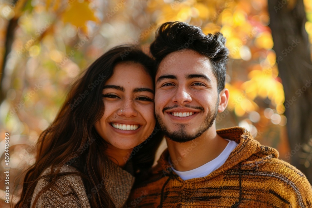 Portrait of a grinning latino couple in their 20s dressed in a comfy fleece pullover over background of autumn leaves Portrait of a grinning latino couple in their 20s dressed in a comfy fleece pullover over background of autumn leaves