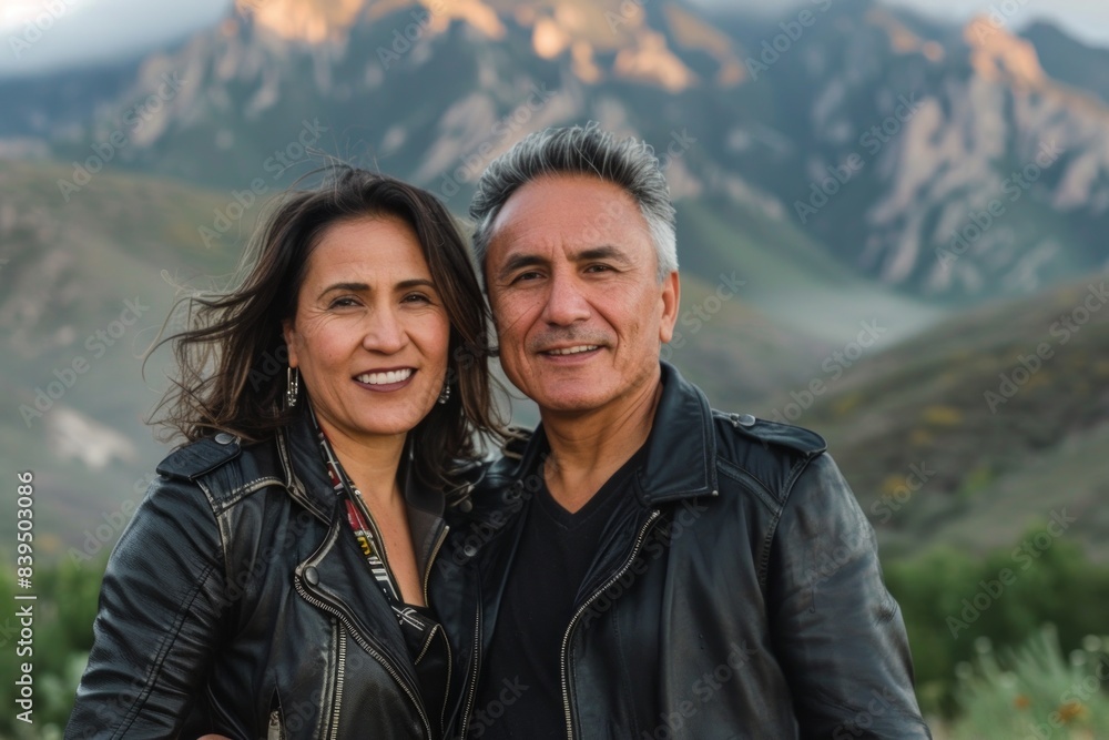Portrait of a happy latino couple in their 40s sporting a classic leather jacket in backdrop of mountain peaks Portrait of a happy latino couple in their 40s sporting a classic leather jacket in backdrop of mountain peaks