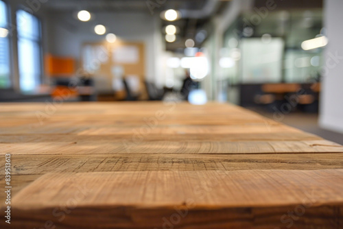 A wooden desk in the foreground with a blurred background of a tech startup office. The background includes modern workstations.