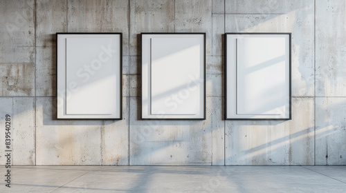 Three blank mockup posters hanging against concrete wall.